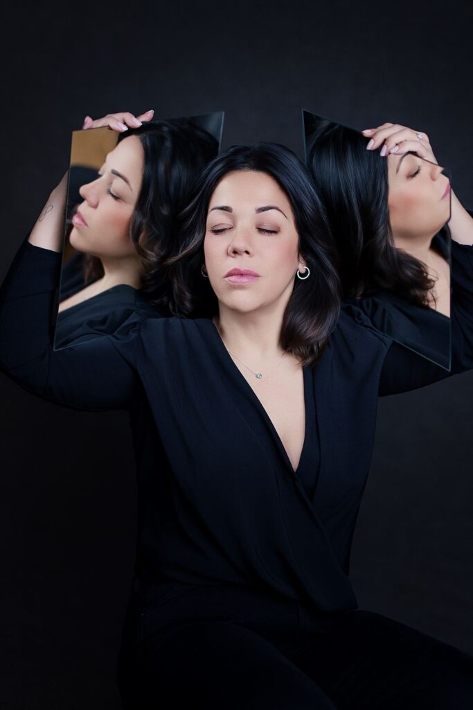 Yassmina Lasso sosteniendo dos espejos que reflejan su rostro, imagen del concepto de CÍRCULO